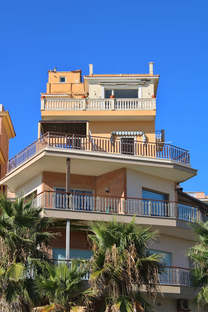 A stylish angular apartment building in Nettuno, Italy under a bright blue sky.